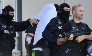 Yassin Salhi entre des policiers lors de la perquisition à son domicile le 28 juin 2015 à Saint-Priest