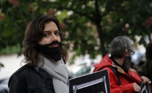 Une jeune femme portant une fausse barbe pour protester contre le sexisme, mercredi 11 mai, à Paris.