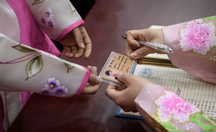 Une Nord-coréenne présente sa carte d'identité pour pouvoir voter, le 10 mars 2019 à Pyongyang.