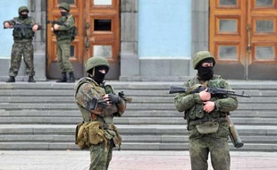 Des hommes non-identifiés en uniforme et armés gardent l'entrée du bâtiment abritant le gouvernement de Crimée, à Simferopol le 2 mars 2014.