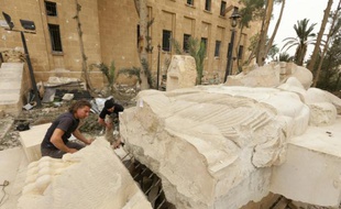 Bartosz Markowski, de l'université de Varsovie, et Robert Zukowski (c), de l'Académie polonaise des Sciences, inspectent une statue à l'entrée du musée de Palmyre, en Syrie, le 9 avril 2016