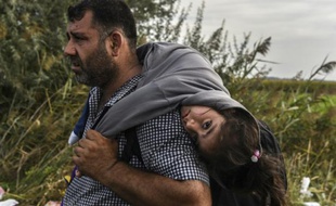 Un réfugié sa fille sur le dos le 14 septembre 2015 à Horgos en Serbie àla frontière avec la Hongrie