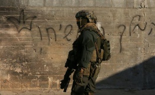 Un soldat israélien devant la maison palestinienne incendiée par des colons israéliens en Cisjordanie, le 31 juillet 2015