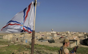 Novembre 2014, aux abords d'un village chrétien situé à 30 km au nord de Moussoul, en Irak. Un soldat de Dwekh Nawsha devant le drapeau du parti Assyrien, lors d'une surveillance (photo d'archives).