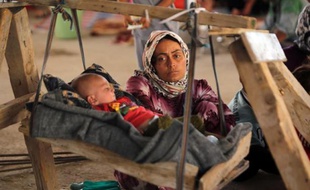 Une femme irakienne yazidi, qui a fui sa maison attaquée par des combattants de l'EI, regarde son bébé dans un immeuble en construction de la banlieue de Dohouk où ils ont trouvé refuge, le 16 août 2014