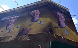 Des passants devant un panneau représentant des joueurs de l’équipe de football ukrainienne, à Kiev, le 7 juin 2021.