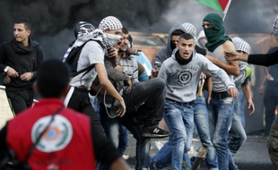 Un Palestinien lanceur de pierre est porté par des camarades après avoir été blessé lors de heurts avec les forces israéliennes à Beit El près de Ramallah le 9 octobre 2015