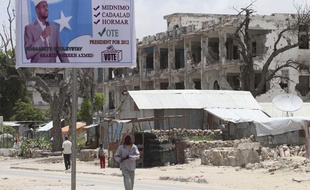 Un homme passe devant une affiche de campagne du président Sheikh Sharif Ahmed, à Mogadicio, le 9 septembre 2012.