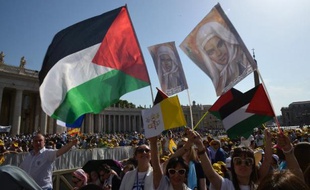Des fidèles place Saint-Pierre avec des drapeaux palestiniens et les portraits de deux religieuses palestiniennes canonisées le 17 mai 2015 au Vatican