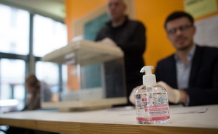 Du gel hydroalcoolique utilisé dans un bureau de vote.