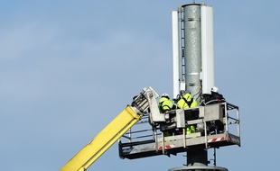 Des techniciens d'une société de télécommunications réparent une antenne de téléphonie mobile.
