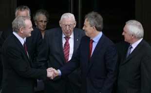 Le Premier ministre britannique Tony Blair serre la main au catholique Martin McGuinnes, investi vice-Premier ministre de l'Irlande du Nord. Derrière eux, le protestant Ian Paisley, nommé Premier ministre le 8 mai 2007.