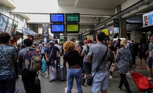 Des passagers rassemblés devant le point d'information de la SNCF, après une panne à la gare Montparnasse à Paris, le 18 août 2018.