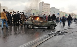 Des manifestants iraniens se rassemblent autour d'une voiture en flammes lors d'une manifestation contre l'augmentation du prix de l'essence dans la capitale, Téhéran, le 16 novembre 2019.
