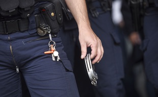 Un policier tenant des menottes. (Illustration)