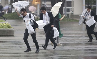 Des employés de bureau courent sous la pluie à l'approche du typhon, à Kanagawa, près de Tokyo, le 28 juillet 2018.