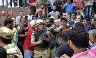 Un soldat pointe son arme sur la foule de manifestants, devant la mosquée Al-Fath, au Caire, le 17 août 2013