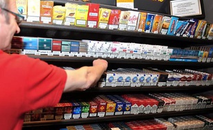 Un buraliste devant ses rayons de paquets de cigarette