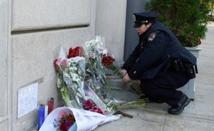 Une policière arrange des fleurs devant le consulat de France à New York, le 14 novembre 2015
