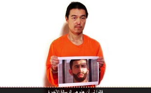 Image extraite d'une vidéo diffusée sur YouTube le 27 janvier 2015 montrant le Japonais Kenji Goto tenant une photo présentée comme étant celle du pilote jordanien Maaz Al-Kassasbeh, tous deux otages du groupe Etat islamique