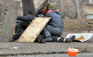 Des manifestants se protègent des tirs des snipers, rue Institutskaya, à Kiev, le 20 février 2014.