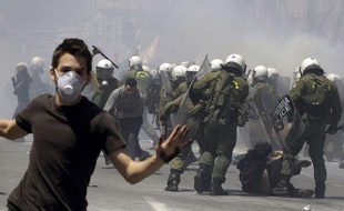 Un jeune manifestant s'enfuit alors que d'autres sont frappés à coups de matraques par la police mercredi 11 mai 2011 à Athènes (Grèce). La police anti-émeute a utilisé beaucoup de gaz lacrymogènes pour disperser les jeunes jetant des pierres.