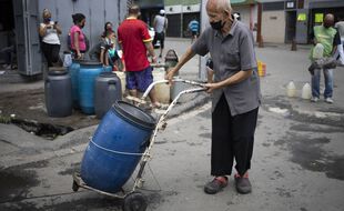 Un homme transporte de l'eau jusqu'à chez lui afin de pallier la défaillance des services de l'Etat dans les quartiers les plus pauvres de Caracas, le 20 juin 2020.
