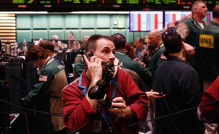 Un trader travaille avec trois téléphones à la bourse de New York, le 7 mars 2011.