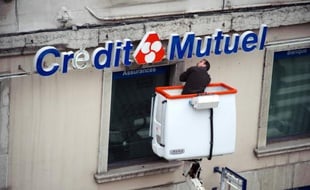 Un technicien répare l'enseigne d'une agence bancaire du Crédit Mutuel, le 10 mars 2009 à Lyon
