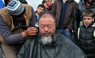 L'artiste chinois Ai Weiwei se fait couper les cheveux par un coiffeur pour attirer l'attention sur le sort des migrants retenus à la frontière gréco-macédonienne dans le camp improvisé d'Idomeni en Grèce le 17 mars 2016
