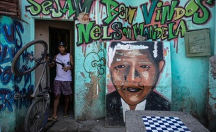 "Soyez bienvenus à Nelson Mandela" peut-on lire au-dessus d'un portrait graffité de Mandela sur le mur d'une maison marqué par des impacts de balles, à l'entrée d'une favela de la zone nord et pauvre de Rio.
