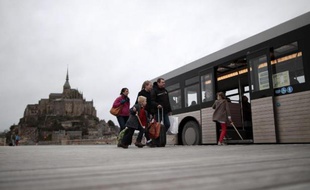 Des touristes montent à bord d'un bus, le 12 décembre 2014, pour se rendre au Mont-Saint-Michel par le nouveau pont-passerelle