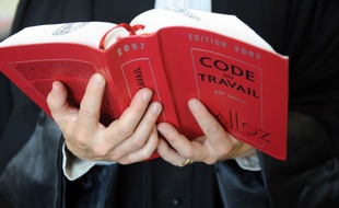 Un avocat tient le Code du travail.