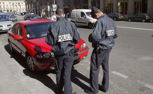 Deux policiers en train de mettre un PV de stationnement à un automobiliste.