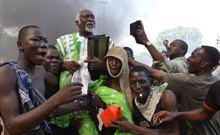 Des manifestants portent un élu de l'opposition devant le Parlement burkinabé à Ouagadougou, le 30 octobre 2014.