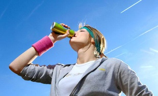 Jeune femme buvant une boisson energisante apres son jogging.
