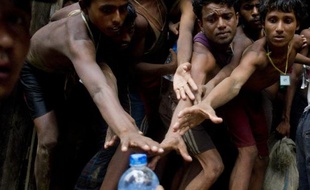Des migrants tentent de récupérer de l'eau dans un camp de réfugiés dans le nord de la Birmanie, le 4 juin 2015