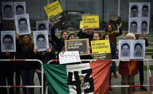 Des membres de l'organisation humanitaire Amnesty International, brandissent des photos d'étudiants disparus au Mexique, lors d'une manifestation à Berlin, devant la chancellerie, le 12 avril 2016