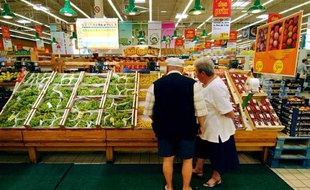 Un couple de retraités devant un étal de fruits et légumes dans une grande surface de Rots (Calvados), le 17 août 2004.