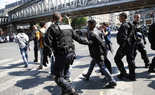 Des policiers conduisent des migrants vers une station de métro après les avoir expulsés de leur campement près de l'église Saint-Bernard.
