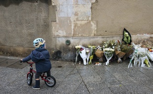 Un enfant devant des bouquets de fleurs déposés près du Carillon, un an après les attentats du 13-Novembre. LEWIS JOLY/SIPA
