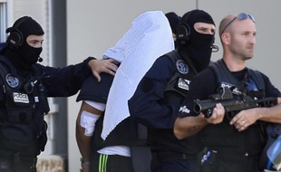 Yassin Salhi escorté par des polciers alors qu'il vient de récupérer son passeport dans son appartement de Saint-Priest avant d'être transféré à Paris, le 28 juin 2015