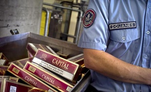 Un douanier devant un stock de cigarettes saisies