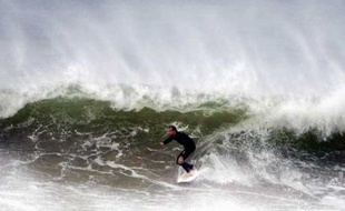 Un homme surfe près de Sydney alors que de gros orages sont attendus sur les cotes australiennes dans la journée, le 20 juin 2007.