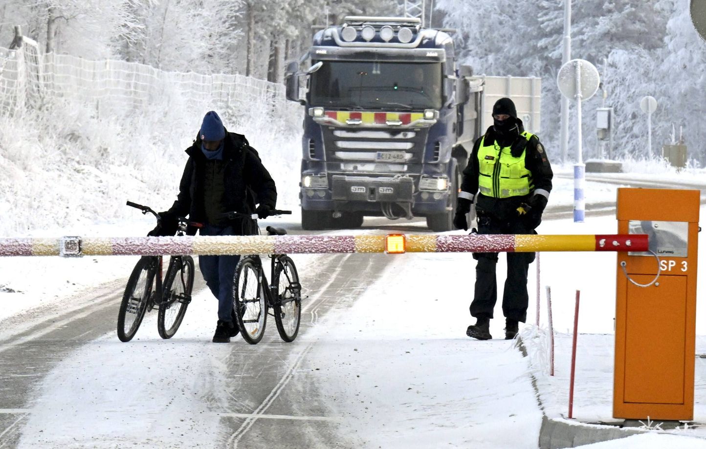 Un garde-frontière finlandais et un migrant avec deux vélos au poste-frontière international de Salla, en Laponie finlandaise, le mardi 21 novembre 2023.