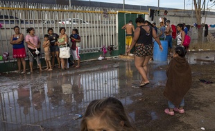 Des migrants venus d'Amérique centrale prennent une douche à Tijuana, à la frontière entre le Mexique et les Etats-Unis.