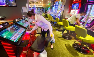 Des agents de nettoyage désinfectent les machines à sous au 3.14 Casino, à Cannes
