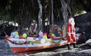 Arrivee d'un pêcheur déguisé en Père Noël pour les enfants de l'école Peverelly à Terre Sainte, à La Réunion, le 10 décembre 2013.