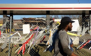 Un homme passe devant la station service dévalisée et incendiée lors d'une émeute au lendemain de la mort de Michael Brown à Ferguson le 16 mars 2015