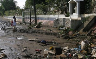 Une Philippine prie dans une rue dévastée par les inondations, à Manille, hier.
